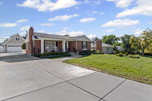 View of front facade with covered porch, a garage, a front lawn, concrete driveway, and brick siding