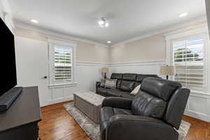 Living area featuring crown molding, wood finished floors, a decorative wall, a wainscoted wall, and recessed lighting