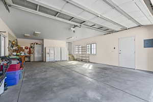 Garage with white fridge with ice dispenser, freestanding refrigerator, and electric panel
