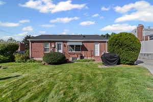 View of front of home with a front yard, brick siding, and entry steps
