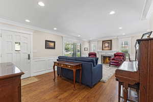 Living room featuring plenty of natural light, wood finished floors, ornamental molding, recessed lighting, and a decorative wall