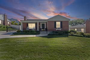 View of front facade featuring a porch, brick siding, a chimney, and a gate