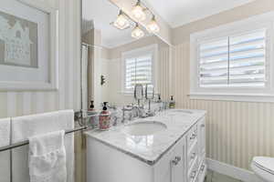 Bathroom featuring wallpapered walls, double vanity, ornamental molding, a chandelier, and light tile patterned flooring