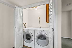 Laundry area featuring washing machine and clothes dryer, dark colored carpet, and a textured ceiling