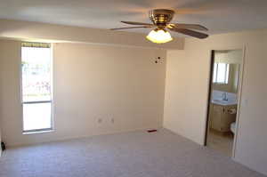 Unfurnished bedroom with carpet, a ceiling fan, and connected bathroom
