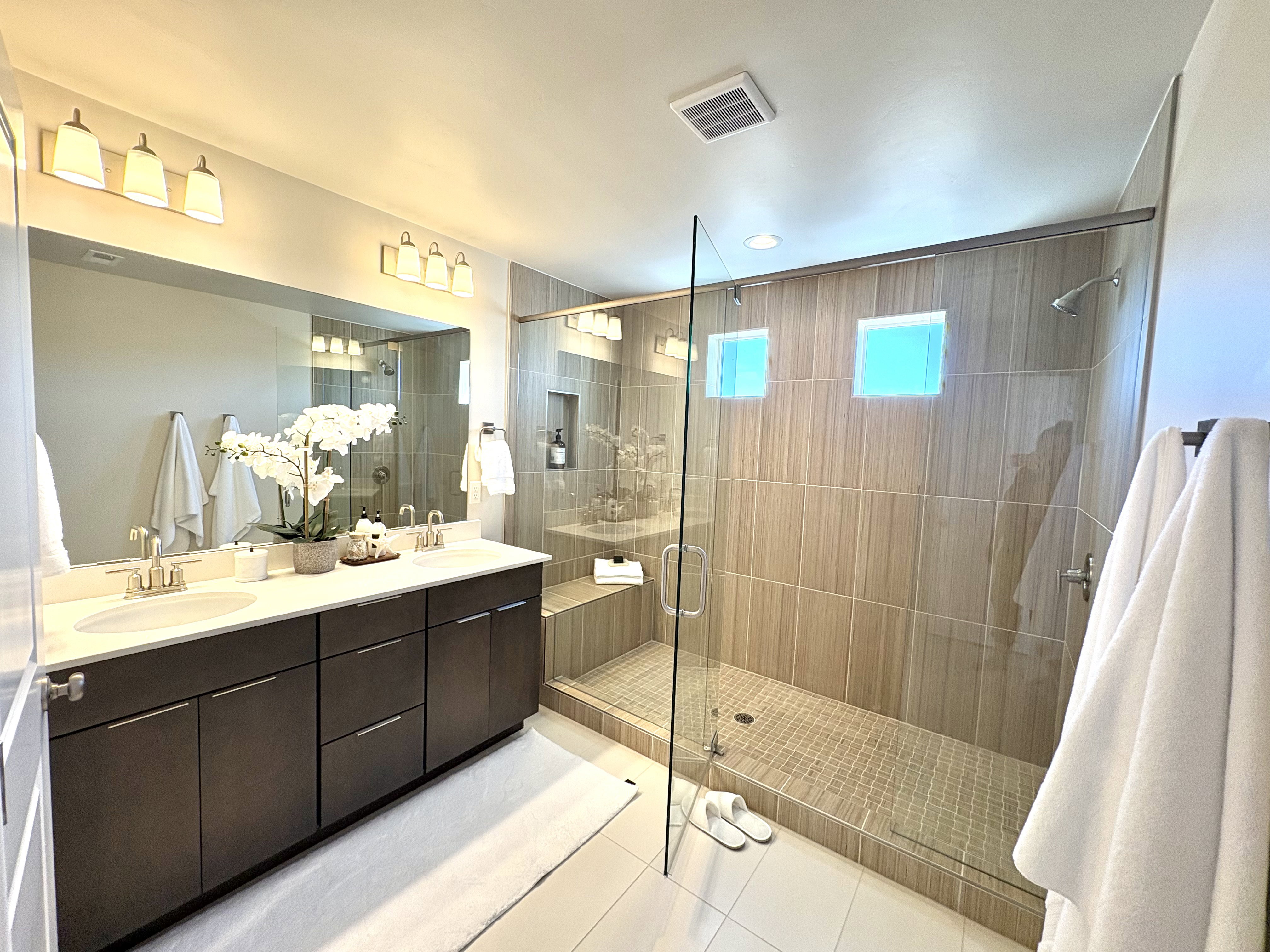 Bathroom with a stall shower, light tile patterned floors, and double vanity