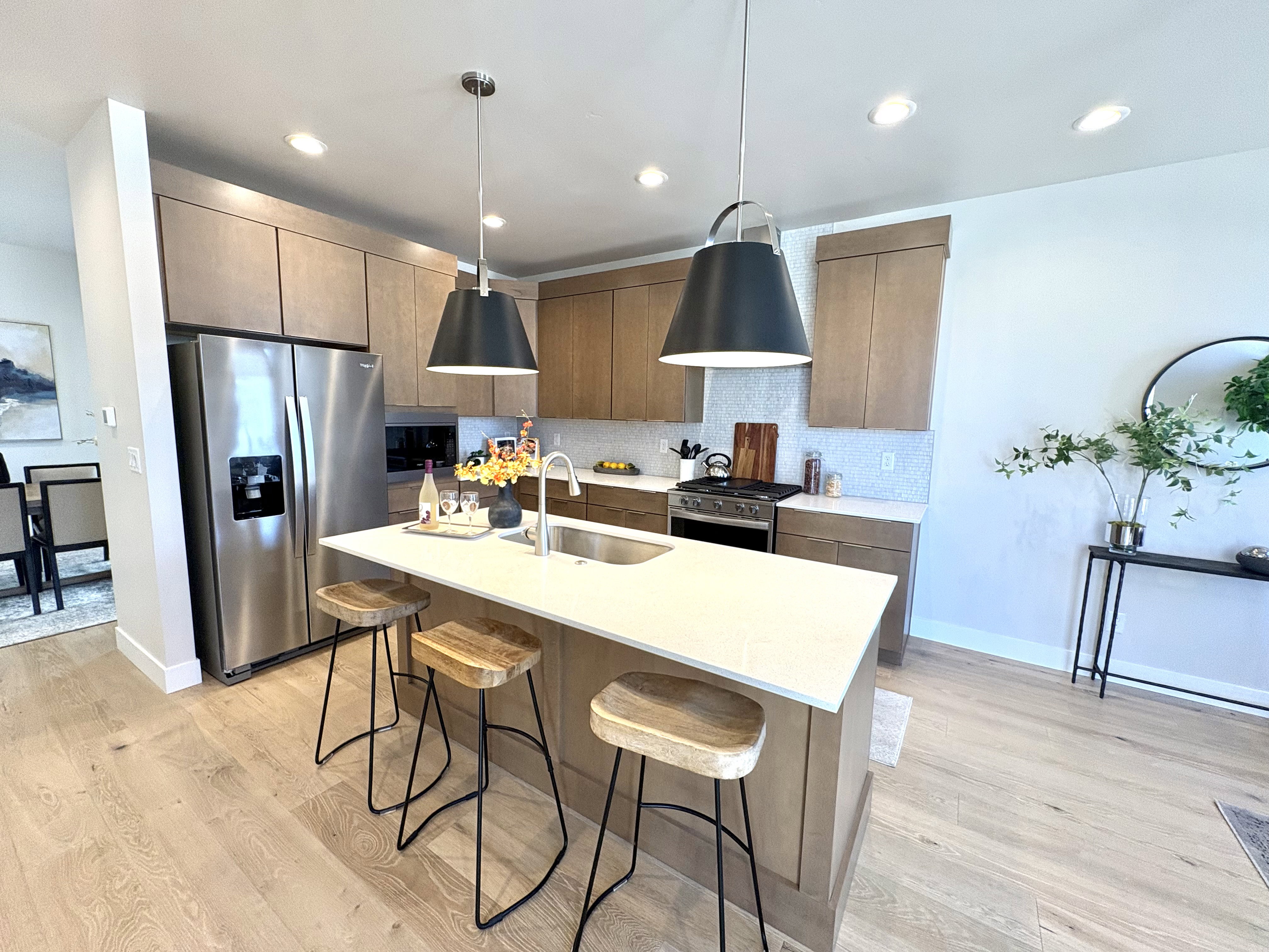 Kitchen featuring stainless steel appliances, a kitchen breakfast bar, an island with sink, recessed lighting, and light stone counters