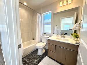 Bathroom featuring shower / bath combo, vanity, and dark tile patterned floors