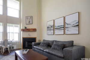 Living area with a fireplace, wood finished floors, and a towering ceiling