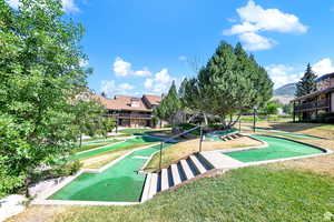 View of property's community featuring a putting area, a lawn, and a mountain view
