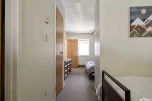 Hallway featuring dark carpet and baseboard heating
