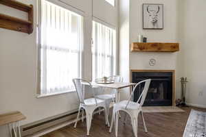 Dining area featuring a fireplace with flush hearth, a baseboard heating unit, and wood finished floors