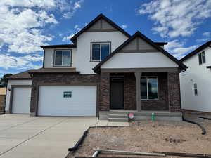 View of front of home featuring stucco siding, driveway, brick siding, and a porch