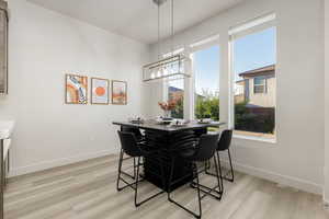 Dining room featuring light wood-type flooring, chandelier and large picture windows.