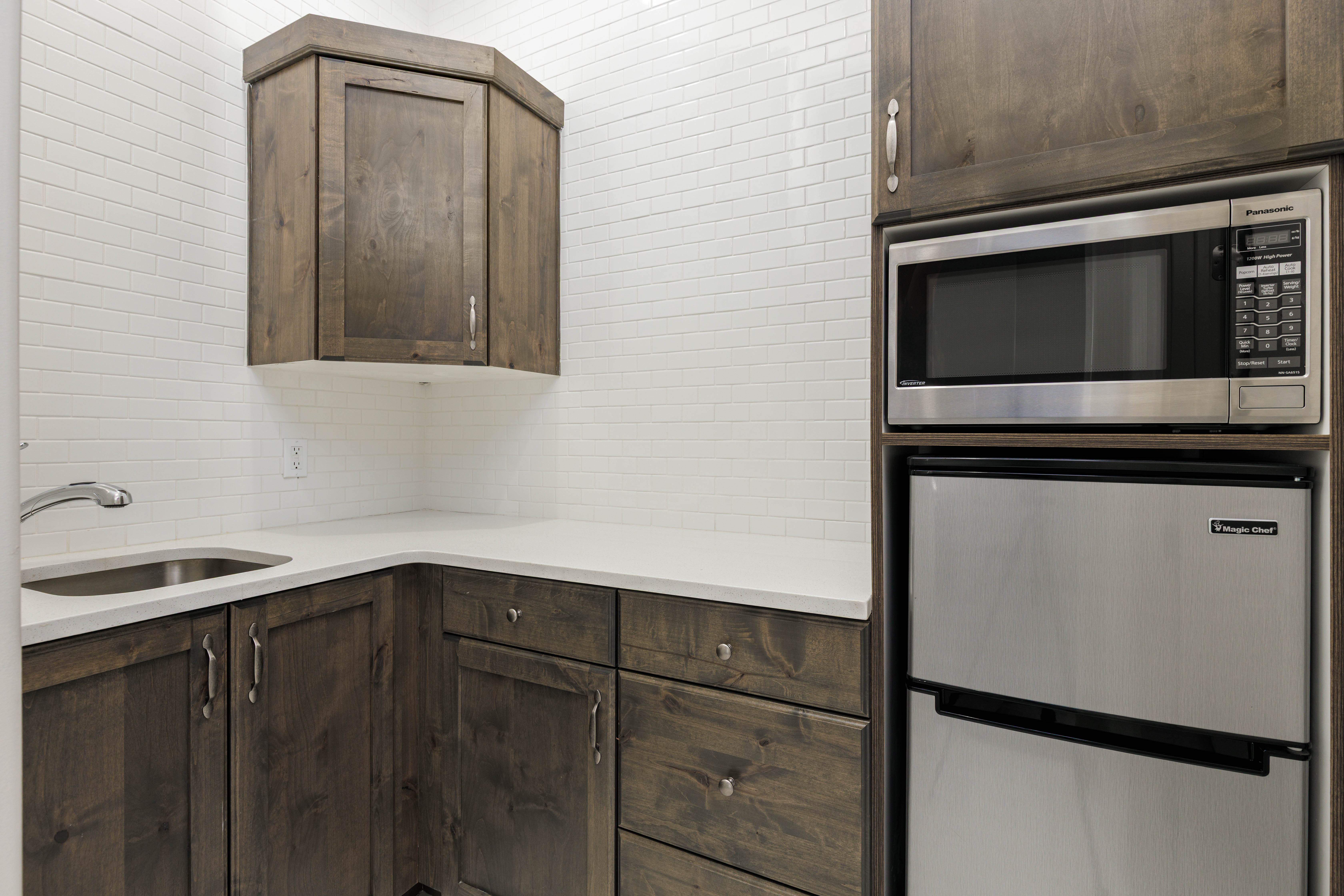 Kitchen featuring stainless steel appliances, dark brown cabinets, light stone counters, and tasteful backsplash