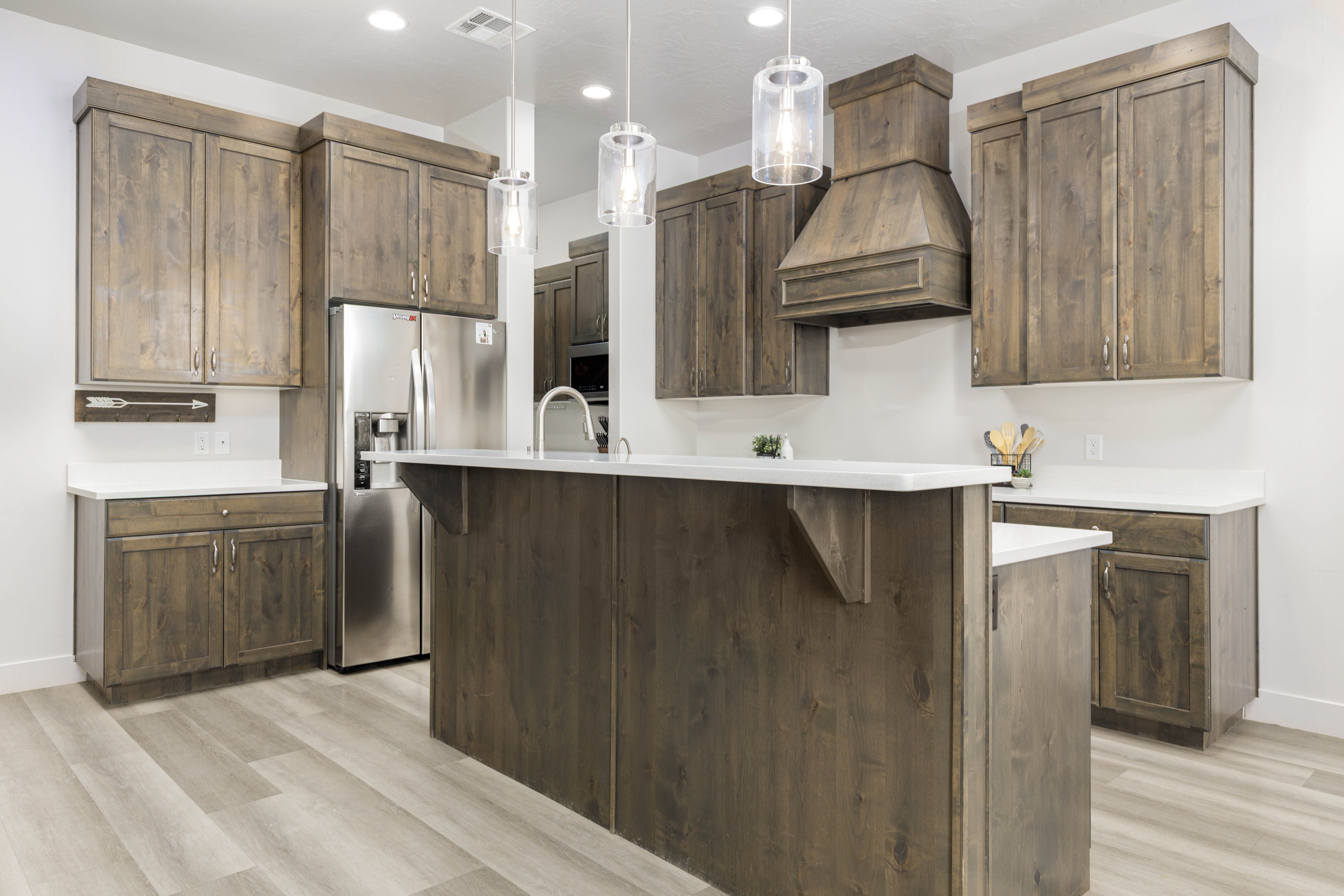 Kitchen featuring decorative light fixtures, stainless steel refrigerator with ice dispenser, light wood finished floors, recessed lighting, and a kitchen bar