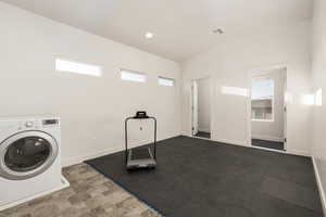 Upstairs laundry room/gym featuring washer / dryer, healthy amount of natural light, recessed lighting and storage room.