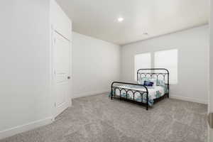 Bedroom featuring light colored carpet, recessed lighting and walk-in closet