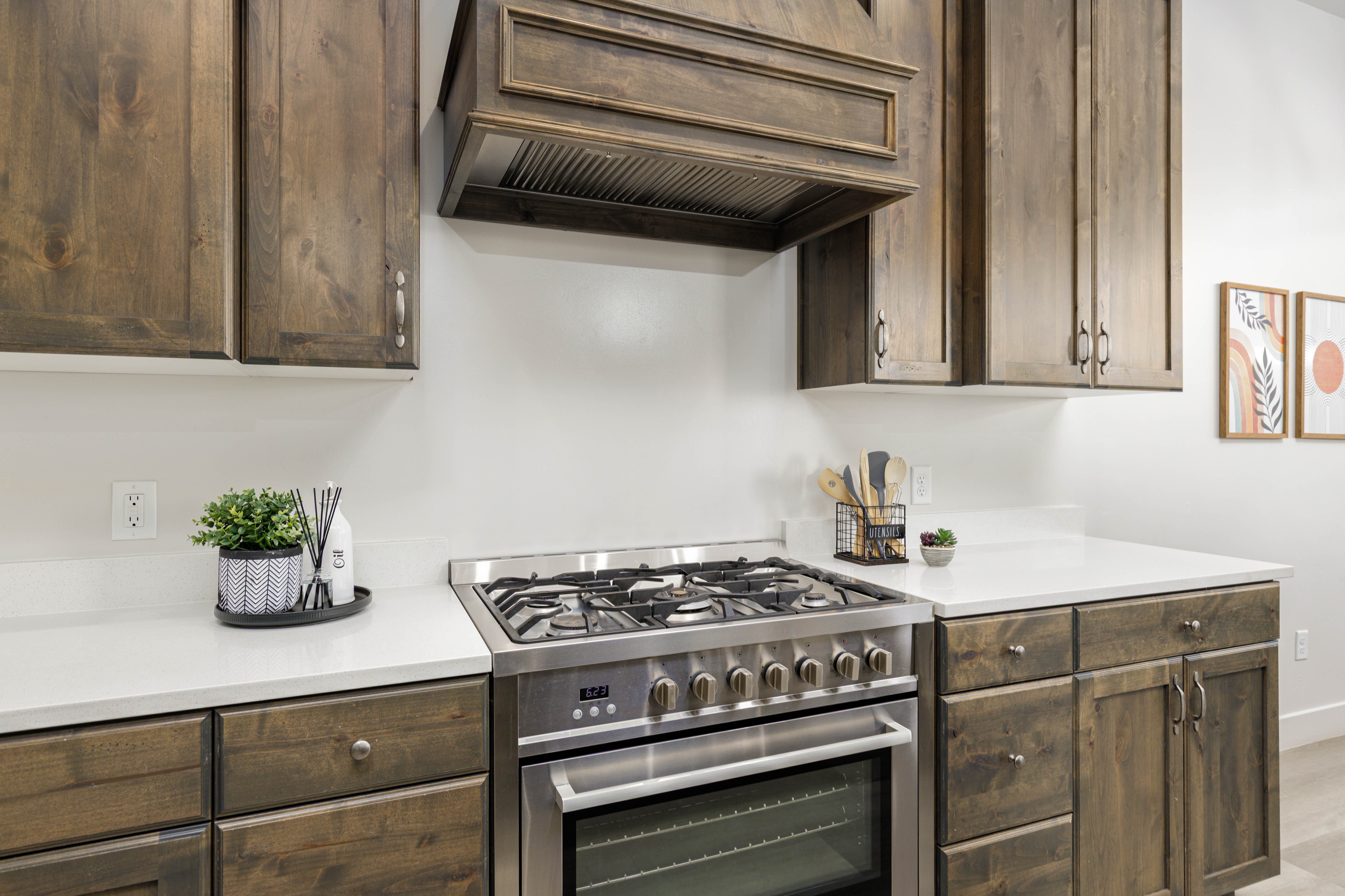 Kitchen featuring stainless steel range with gas stovetop, custom range hood, dark brown cabinets, and light stone counters