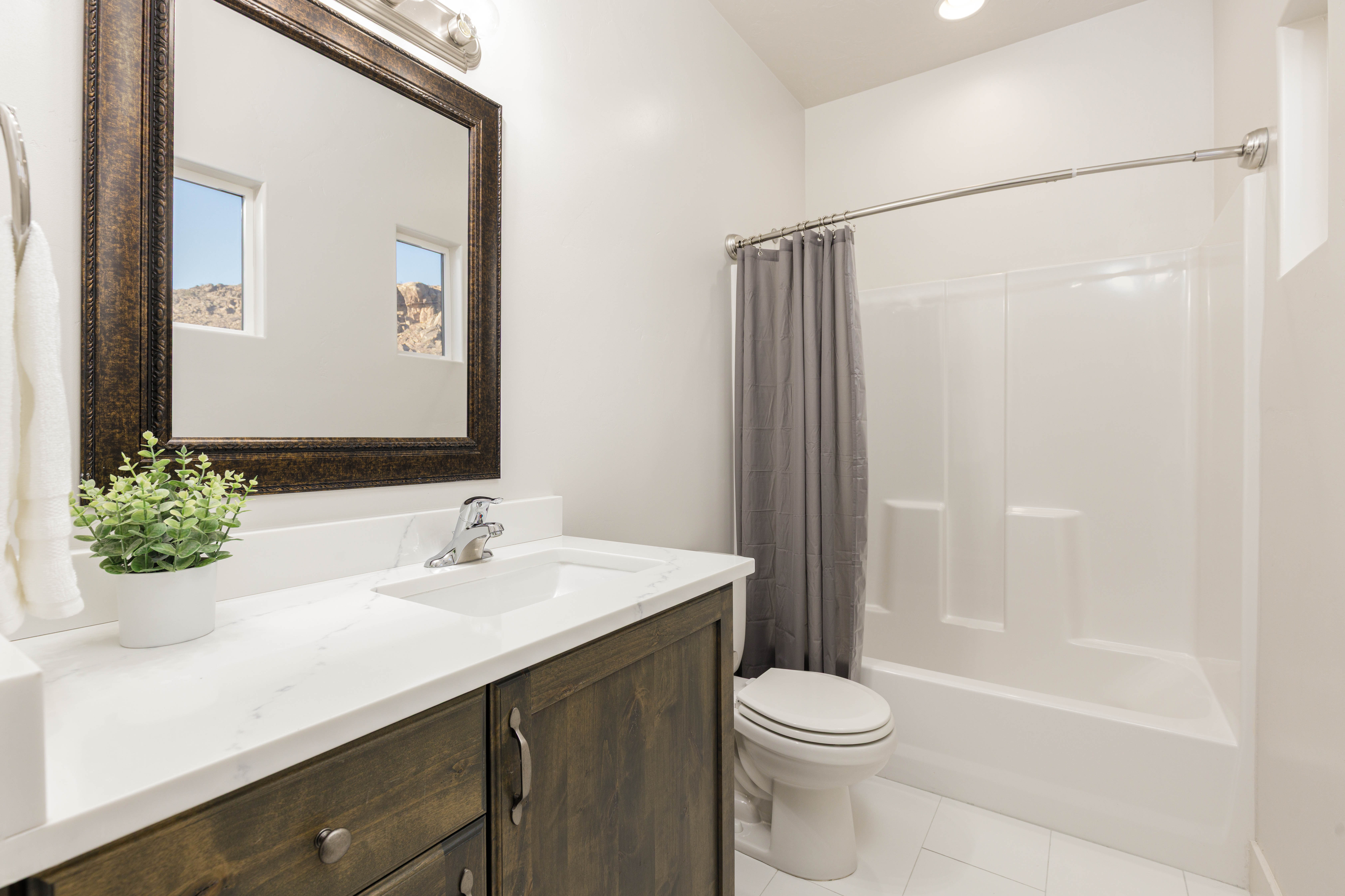 Bathroom featuring shower / bath combination, vanity, light tile floors, vanity lighting and decorative windows for natural lighting