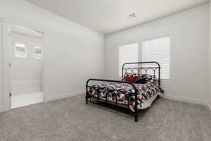 Bedroom with light colored carpet and multiple windows. Shares Jack & Jill bathroom
