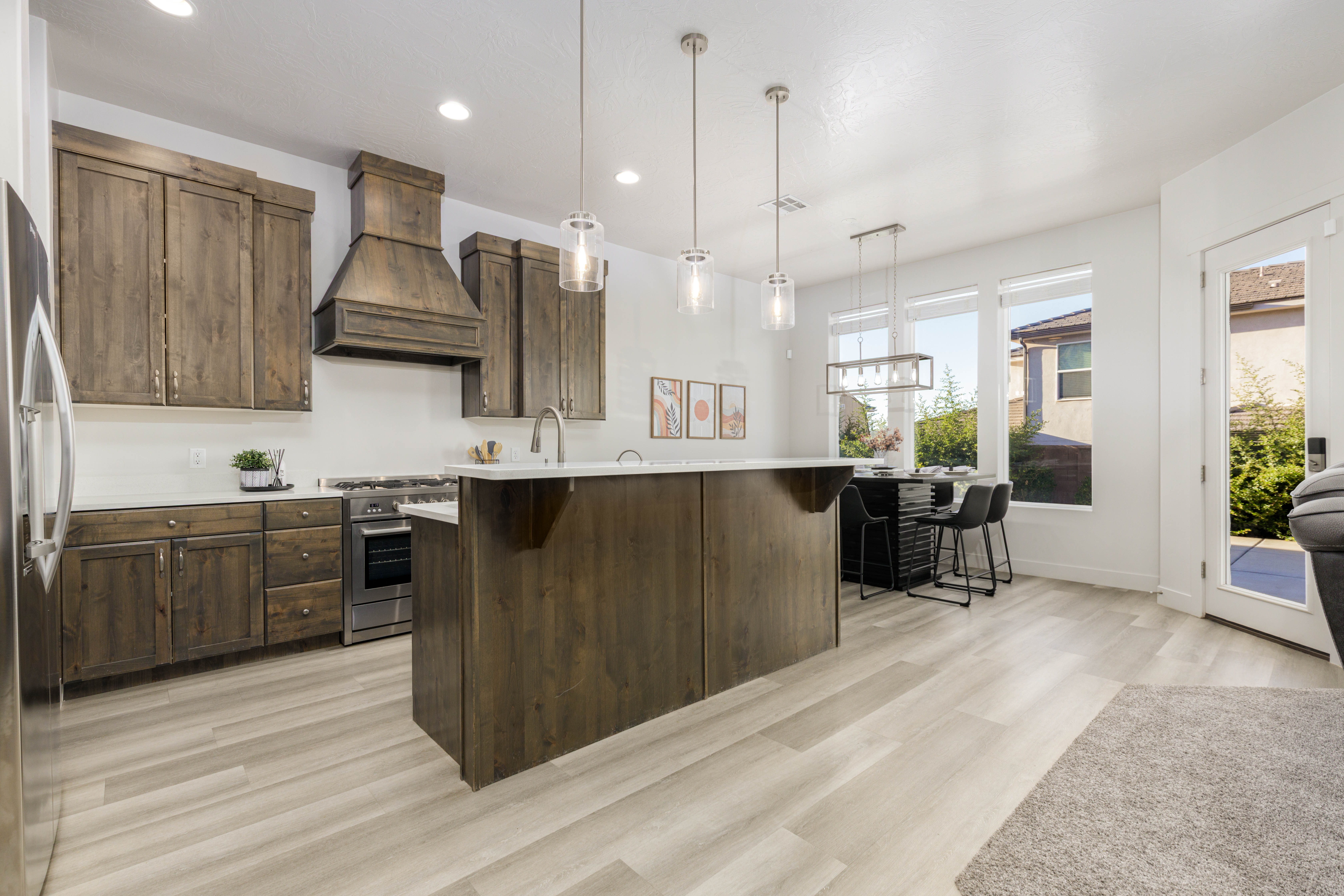 Kitchen with recessed lighting, custom exhaust hood, appliances with stainless steel finishes, pendant lighting, and light wood finished floors