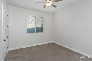 Carpeted spare room featuring baseboards and ceiling fan