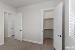 Unfurnished bedroom featuring a spacious closet and light colored carpet