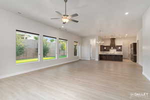 Unfurnished living room featuring a chandelier, light wood finished floors, recessed lighting, and ceiling fan