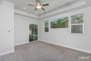 Unfurnished room featuring light carpet, a raised ceiling, a ceiling fan, and recessed lighting