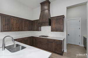 Kitchen featuring backsplash, dark brown cabinetry and light wood-type flooring