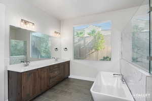 Full bath with a freestanding tub, double vanity, and dark tile patterned floors