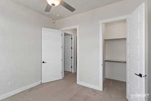 Bedroom featuring light carpet, a walk in closet, and ceiling fan