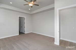 Spare room featuring light colored carpet, recessed lighting, ceiling fan, and a tray ceiling