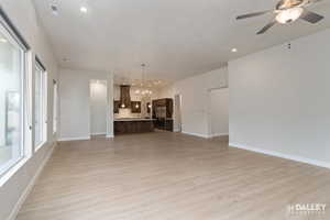 Unfurnished living room with light wood finished floors, a chandelier, recessed lighting, and a ceiling fan