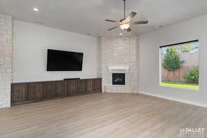 Unfurnished living room with light wood finished floors, ceiling fan, a fireplace, and recessed lighting