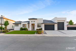 View of front of property featuring stone siding, an attached garage, stucco siding, concrete driveway, and a front lawn