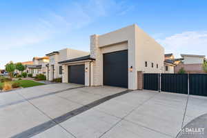 Contemporary home with stucco siding, driveway, an attached garage, and a residential view