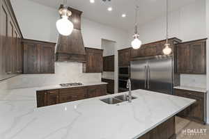 Kitchen featuring dark brown cabinetry, tasteful backsplash, light stone countertops, and recessed lighting