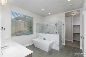 Full bath featuring a soaking tub, a marble finish shower, double vanity, a spacious closet, and tile patterned flooring