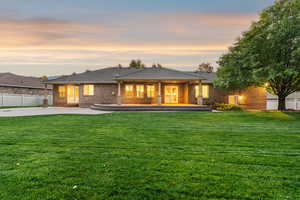 Back of house at dusk with a patio area, brick siding, and roof with shingles
