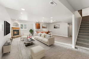 Living area featuring light colored carpet, recessed lighting, a fireplace, and stairway