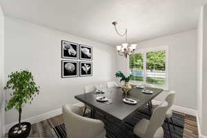 Dining area featuring a chandelier, dark wood-style flooring, and a textured ceiling