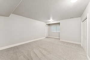 Basement with light carpet and a textured ceiling