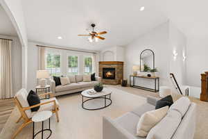 Living area with lofted ceiling, recessed lighting, a stone fireplace, carpet, and ceiling fan