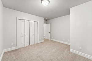 Unfurnished bedroom with carpet flooring, a closet, and a textured ceiling