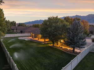 Back of house at dusk featuring a fenced backyard, a mountain view, and a patio