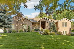 View of front of property featuring a front lawn, brick siding, and a porch