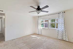 Spare room featuring carpet and ceiling fan