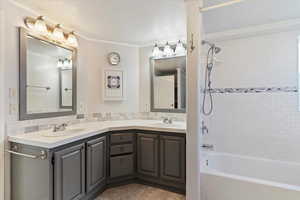 Bathroom with  shower combination, double vanity, light tile patterned floors, and ornamental molding